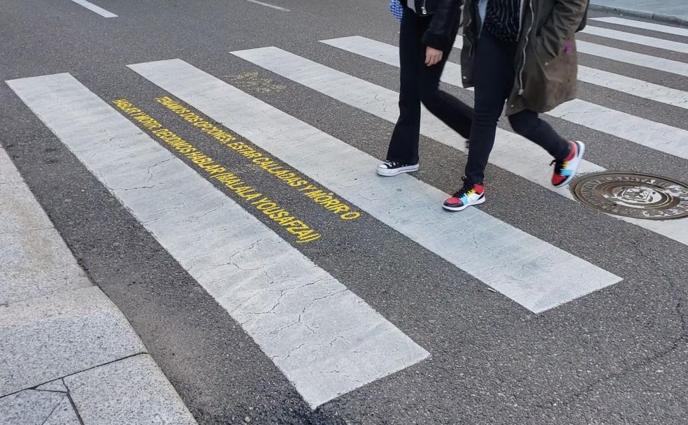 Dos peatones cruzan un 'paso de cebra' junto a una de las frases alusivas. 