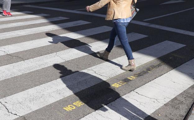 Galería. Una mujer atraviesa un paso de cebra con las frases alusivas al 8M borradas. 