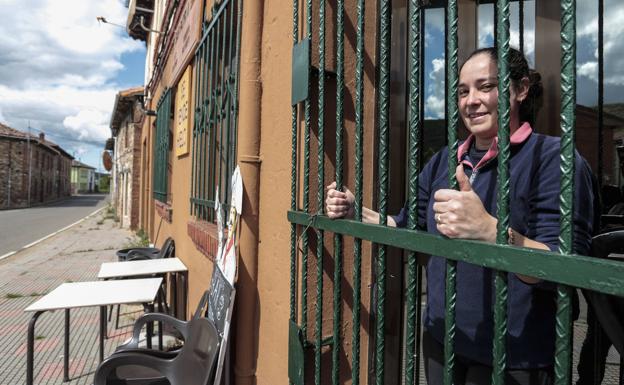 Una mujer cierra la puerta exterior de su negocio por las restricciones. 