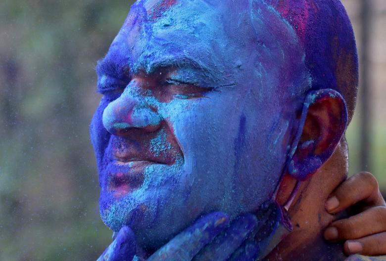 Un hombre reacciona cuando se le aplica polvo de color en la cara durante las celebraciones de Holi en Mumbai, India.