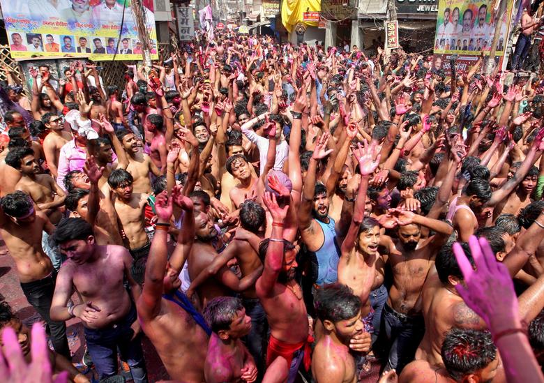 Los hombres vitorean mientras levantan las manos pintadas de colores durante las celebraciones de Holi en Prayagraj, India.