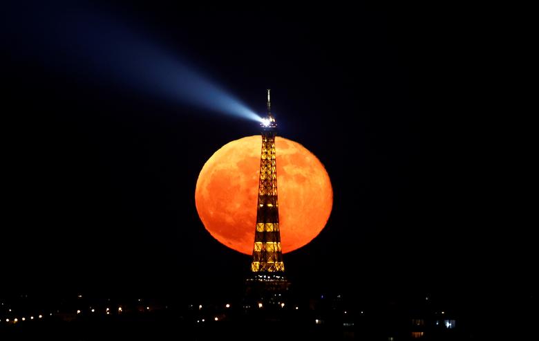 La luna llena, conocida como "Super Pink Moon" se eleva detrás de la Torre Eiffel en París, Francia.