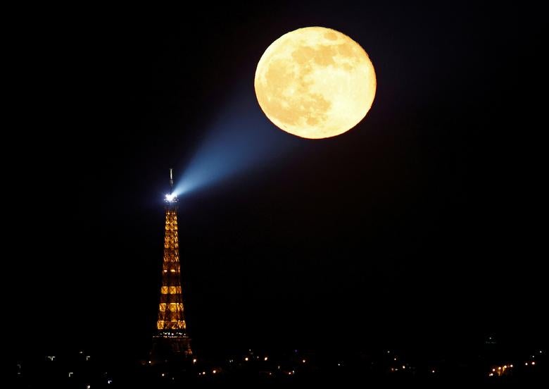 La luna llena, conocida como "Super Pink Moon" se eleva detrás de la Torre Eiffel.