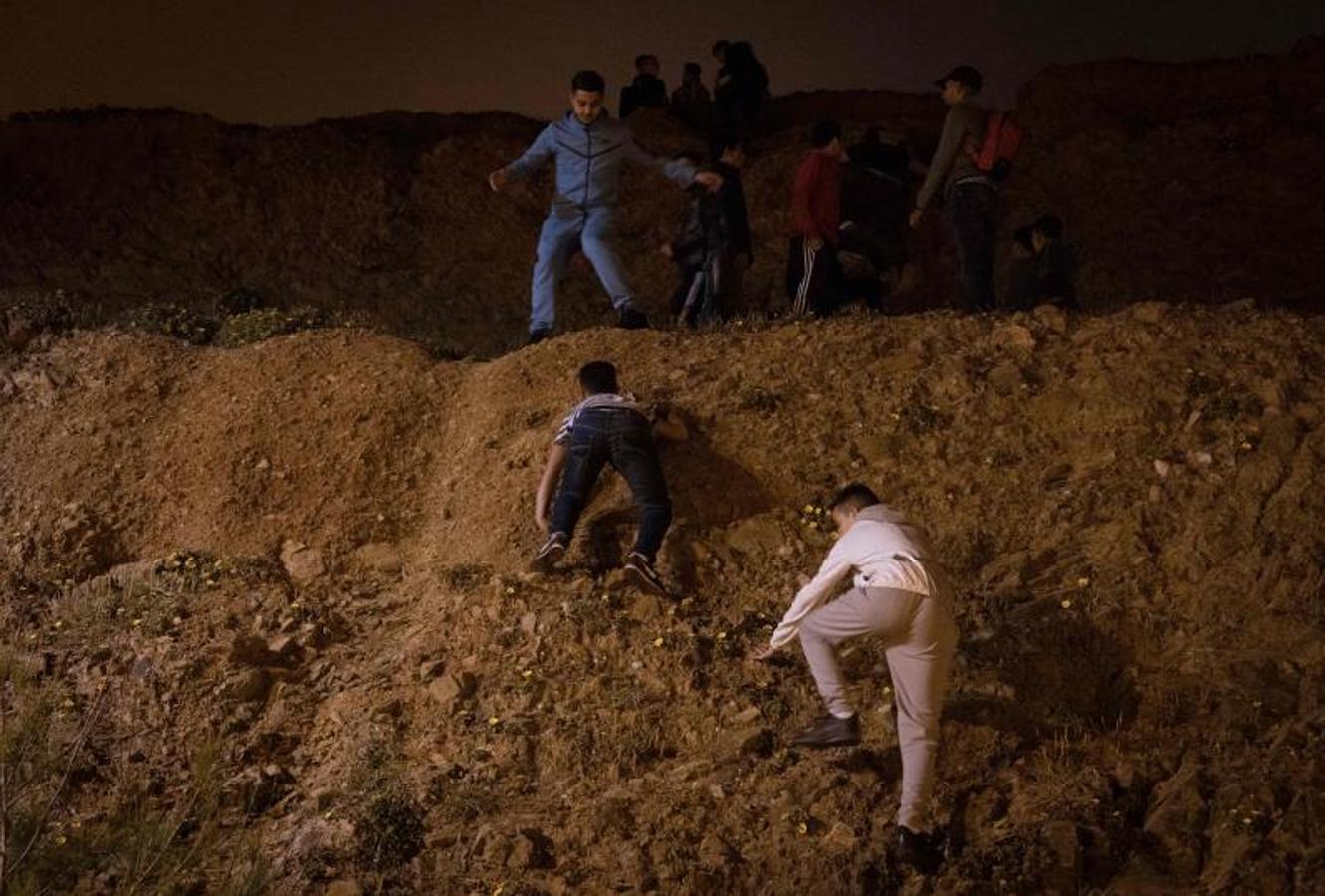 Migrantes marroquíes trepan por un acantilado en la ciudad norteña de Fnideq mientras intentan cruzar la frontera de Marruecos al enclave español de Ceuta.