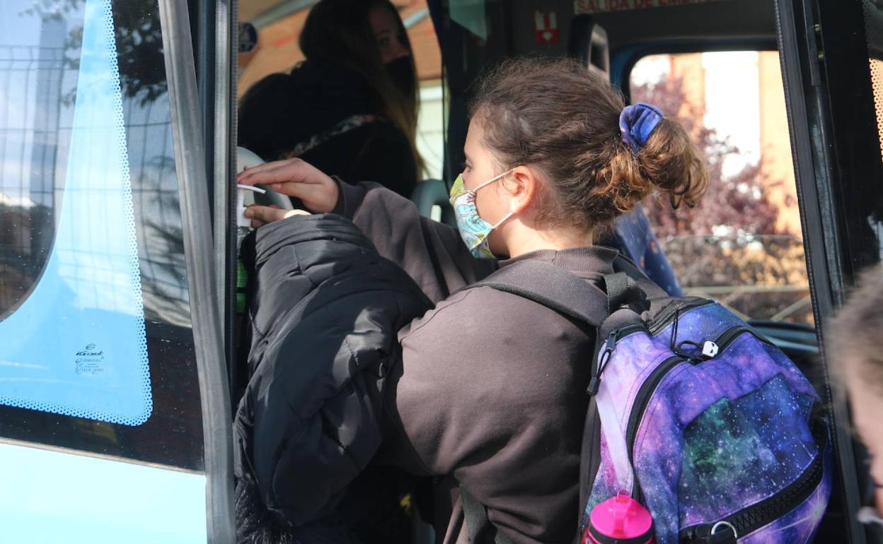 Una alumna se desinfecta las manos al entrar a un bus escolar.