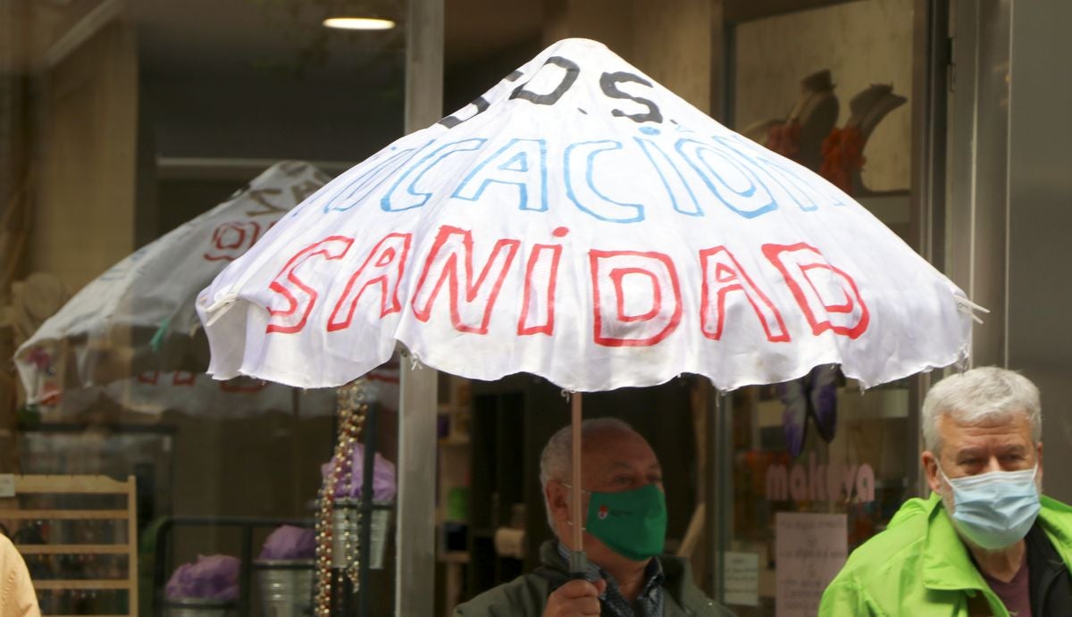 Galería. Uno de los manifestante sostiene un paraguas con lemas por la sanidad y la educación públicas.