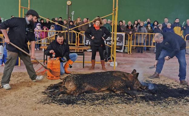 Los vecinos miran cómo se chamusca el cerdo durante la matanza.