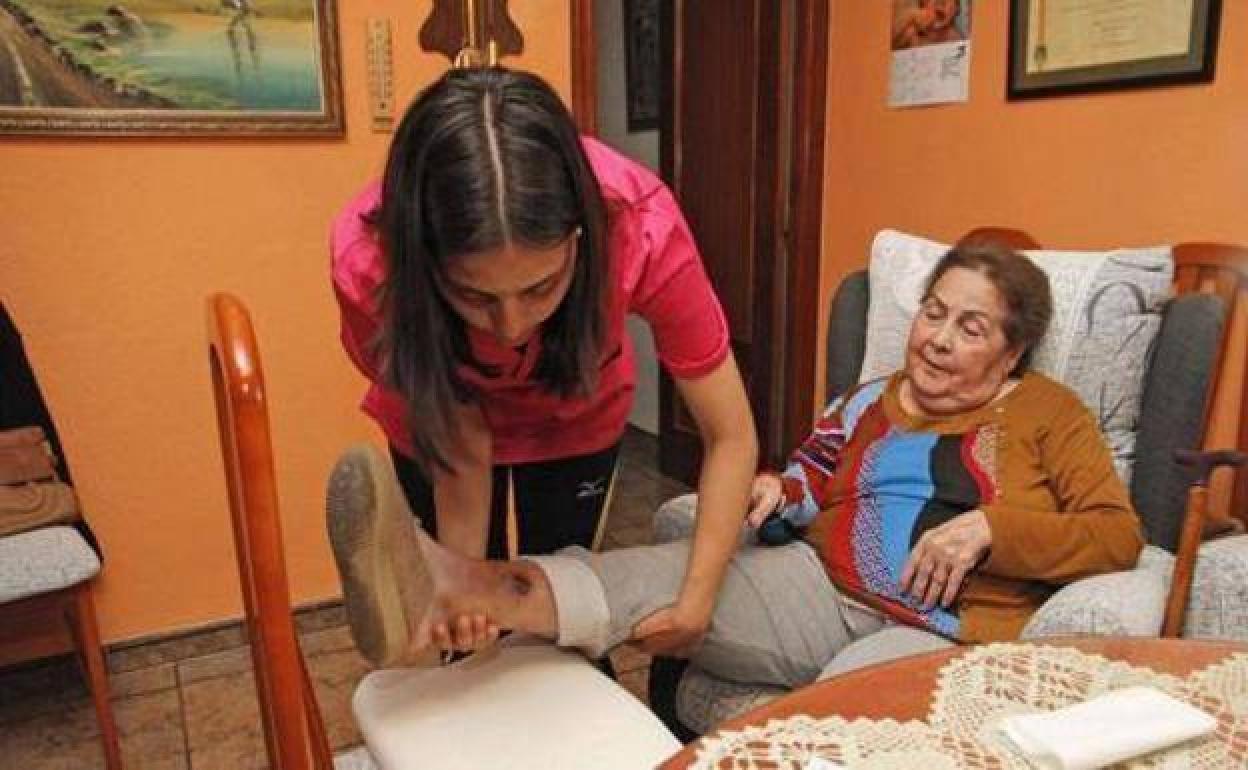 Una joven asiste a una mujer en su domicilio.