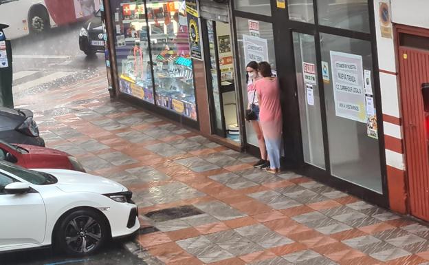 Galería. Dos mujeres se refugian de la lluvia.