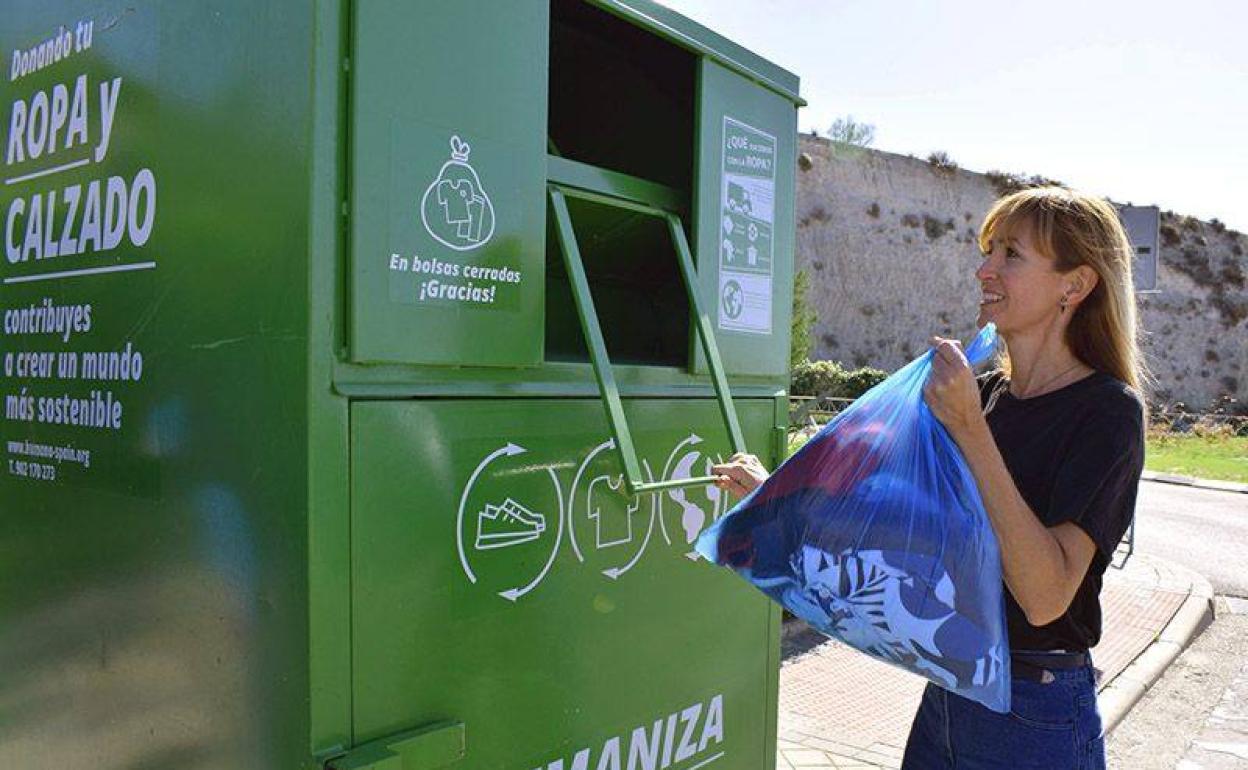 Una mujer recicla ropa en un contenedor de Humana Fundación Pueblo para Pueblo.