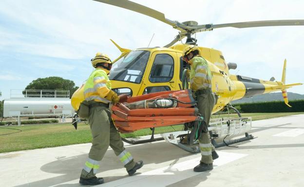 Imagen de varios agentes medioambientales junto a un helicóptero.