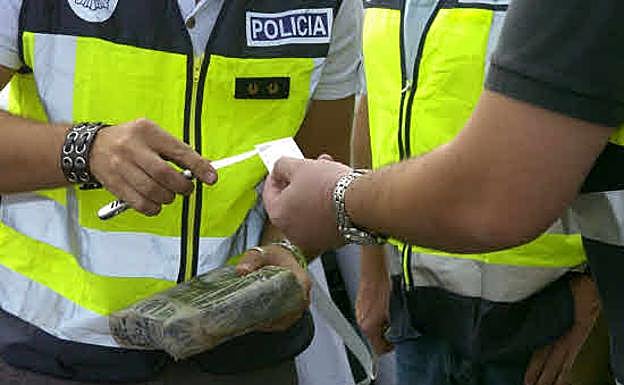 Dos agentes de la Policía Nacional cogiendo una muestra de cocaína para analizar.