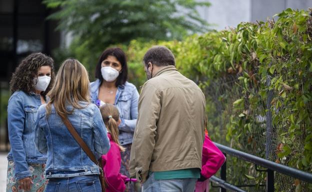 Los padres de las niñas, de espaldas y junto a las menores, esta mañana a la entrada del colegio, charlando con dos integrantes del equipo directivo.