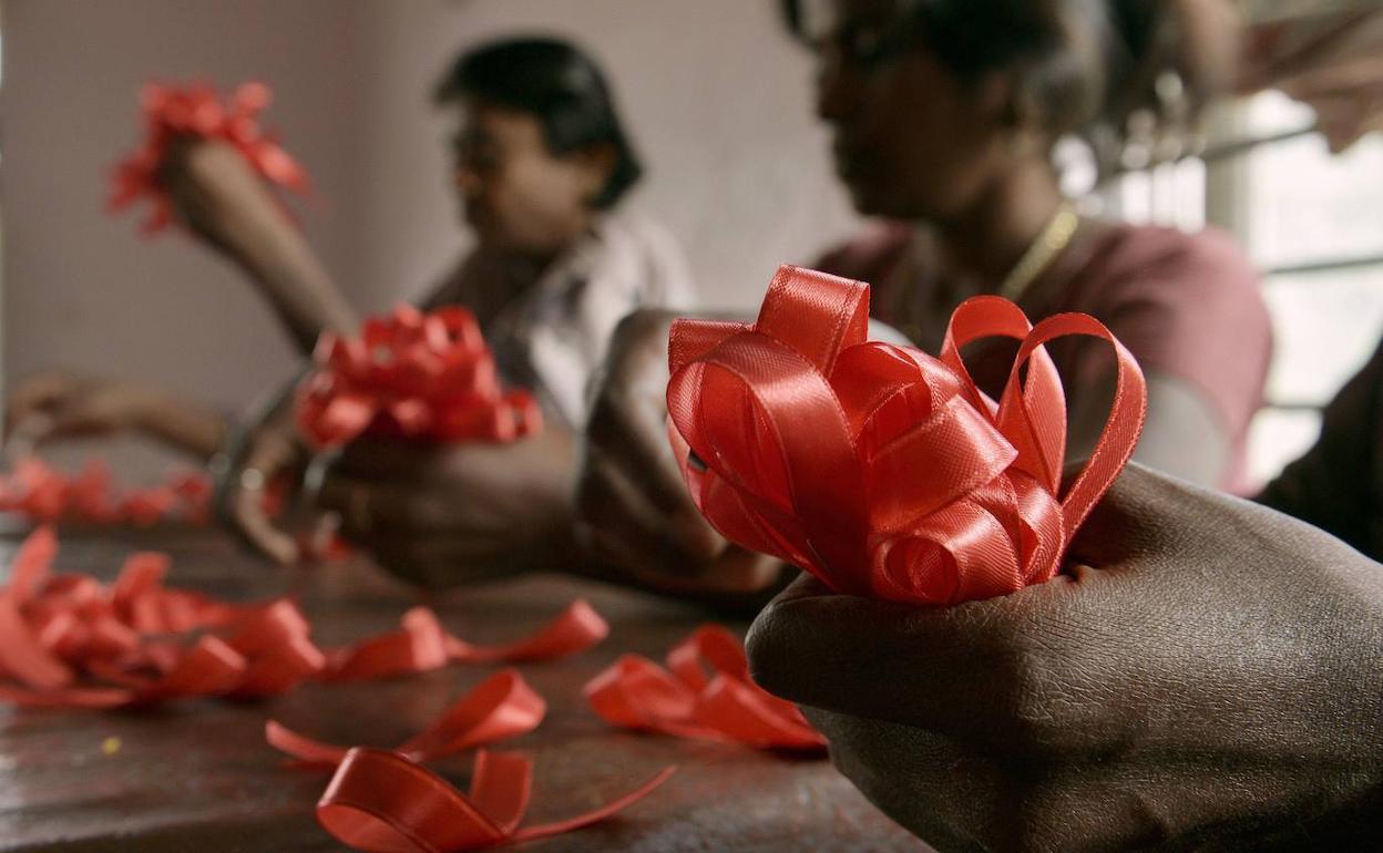 Mujeres seropositivas confeccionan lazos rojos en el centro de Bangalore (India).