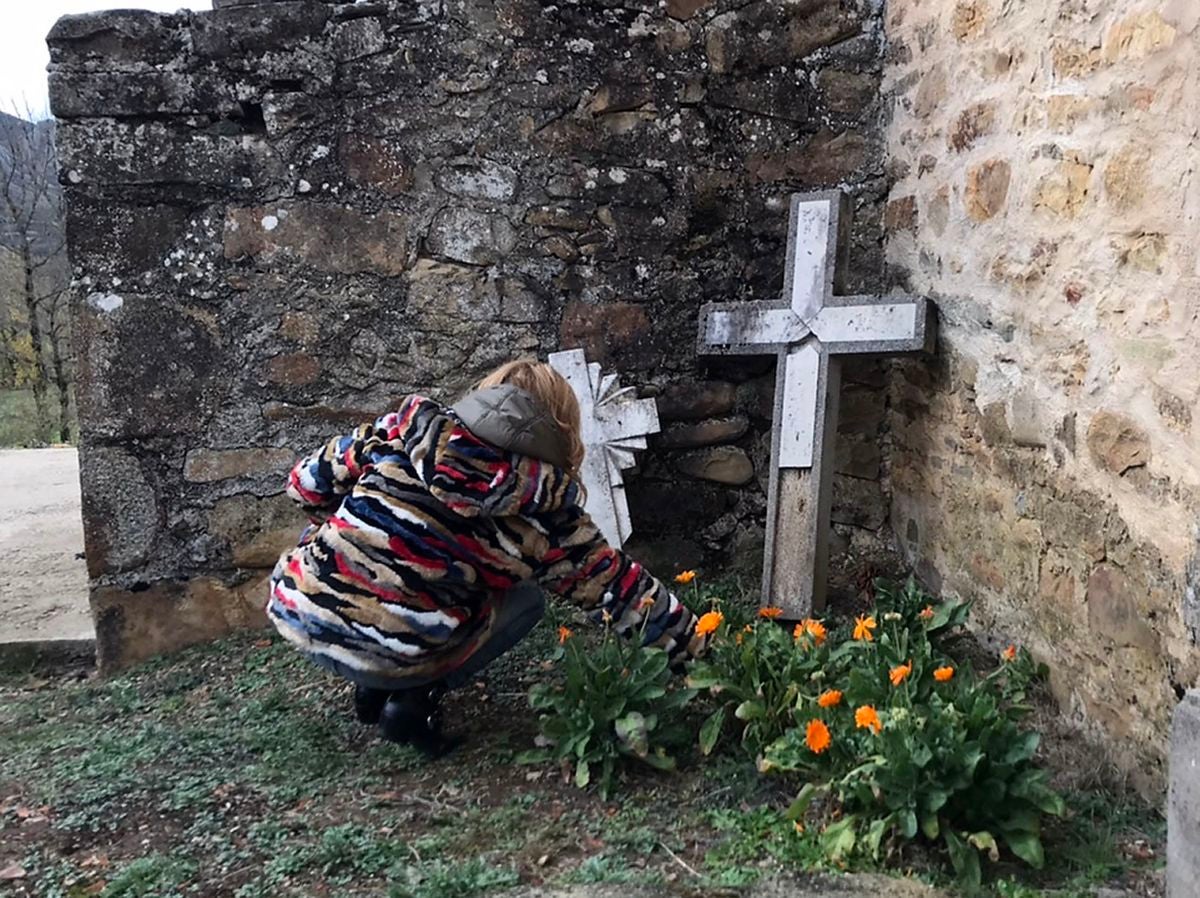 Un grupo de personas adornan las sepulturas en un pueblo de la montaña leonesa antes de la festividad de Todos los Santos.