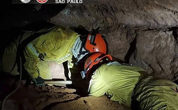 Dos bomberos tratan de rescatar a sus compañeros atrapados en una cueva en Brasil.