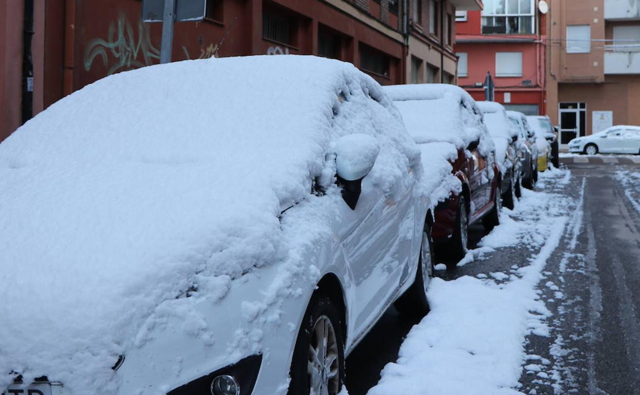 Imagen de vehículos cubiertos por la nieve en una calle de León este domingo. 