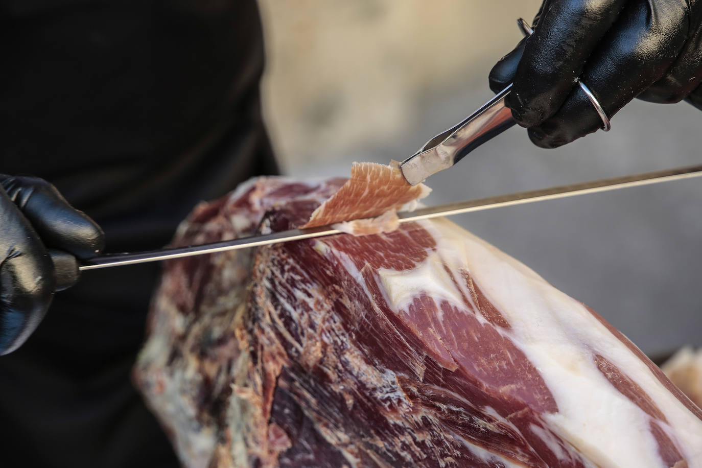 Centenares de personas participan en el corte de platos de jamón por una acción benéfica.