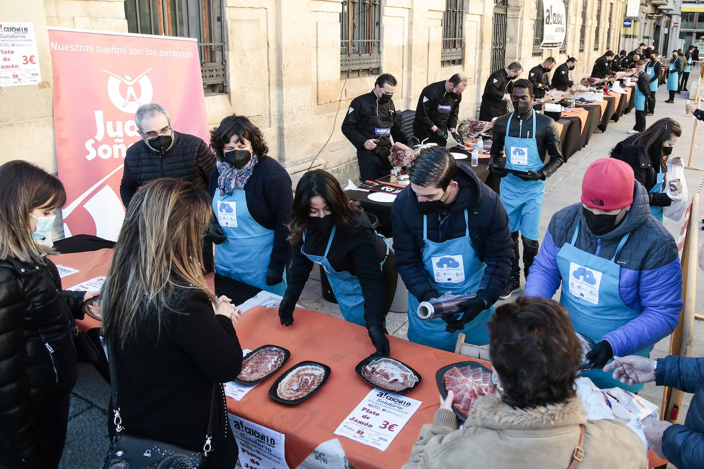 Centenares de personas participan en el corte de platos de jamón por una acción benéfica.