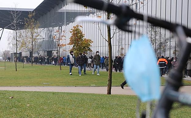 El Palacio de Exposiciones sigue acogiendo la vacunación de la tercera dosis frente a la covid y la gripe. En la imagen, una mascarilla frente a la cola de este martes.