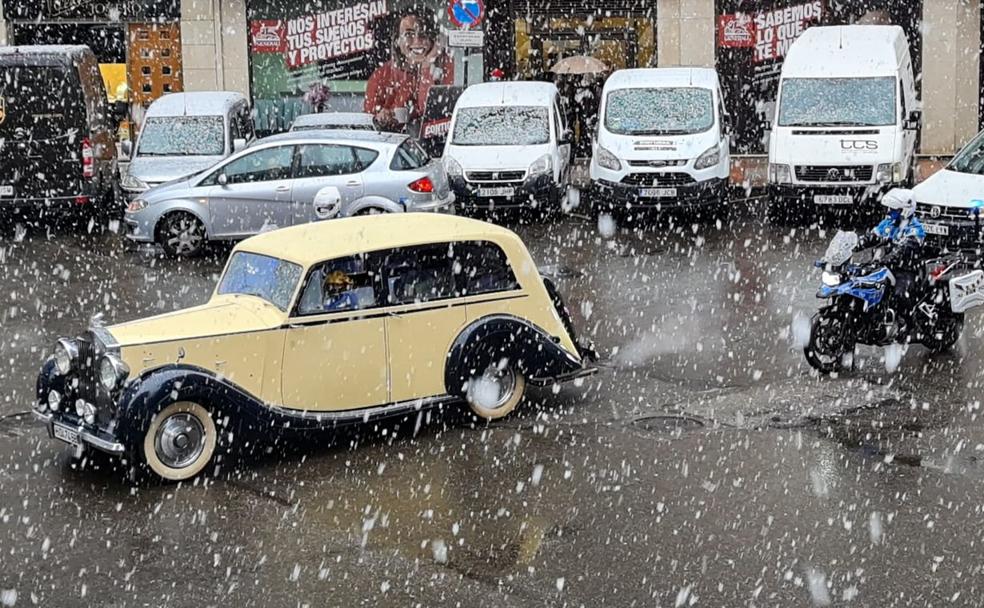 Uno de los coches oficiales de los Reyes Magos, a su paso por León capital entre la nieve y escoltado por la Policía Local. 