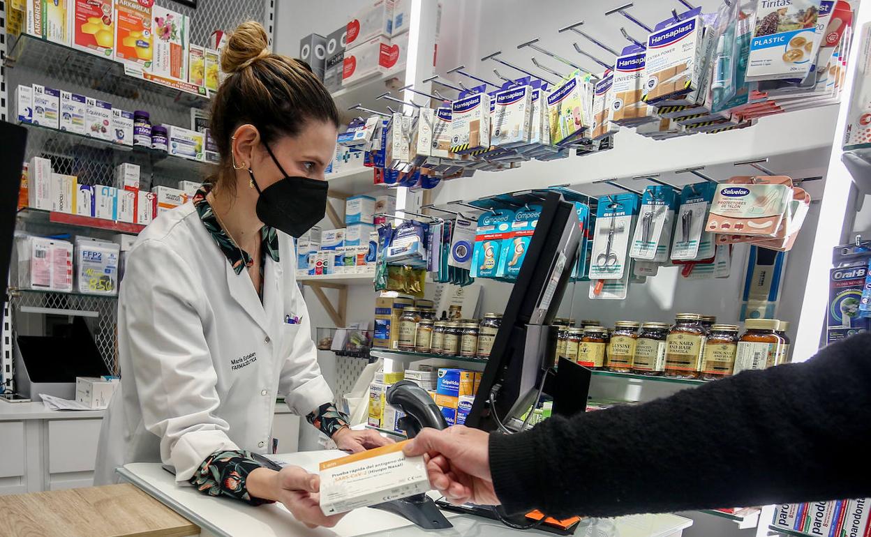 Una farmacéutica vende un test de antígenos a un cliente. 