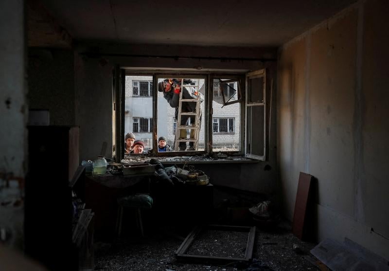 Trabajadores municipales observan una casa destruida en un bombardeo.