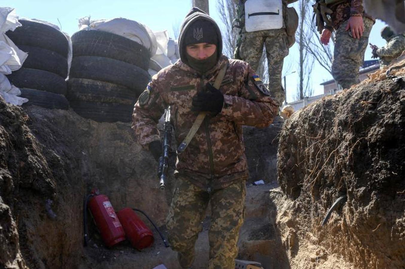 Un soldado ucraniano corre hacia una trinchera militar mientras un avión de combate ruso sobrevuela junto a la escuela militar.