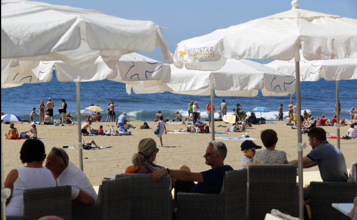 Turistas al sol y en terrazas en una playa de Maspalomas (Gran Canaria).