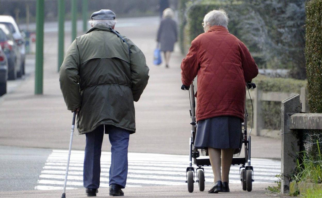 Una pareja de ancianos pasea por la calle de una ciudad.