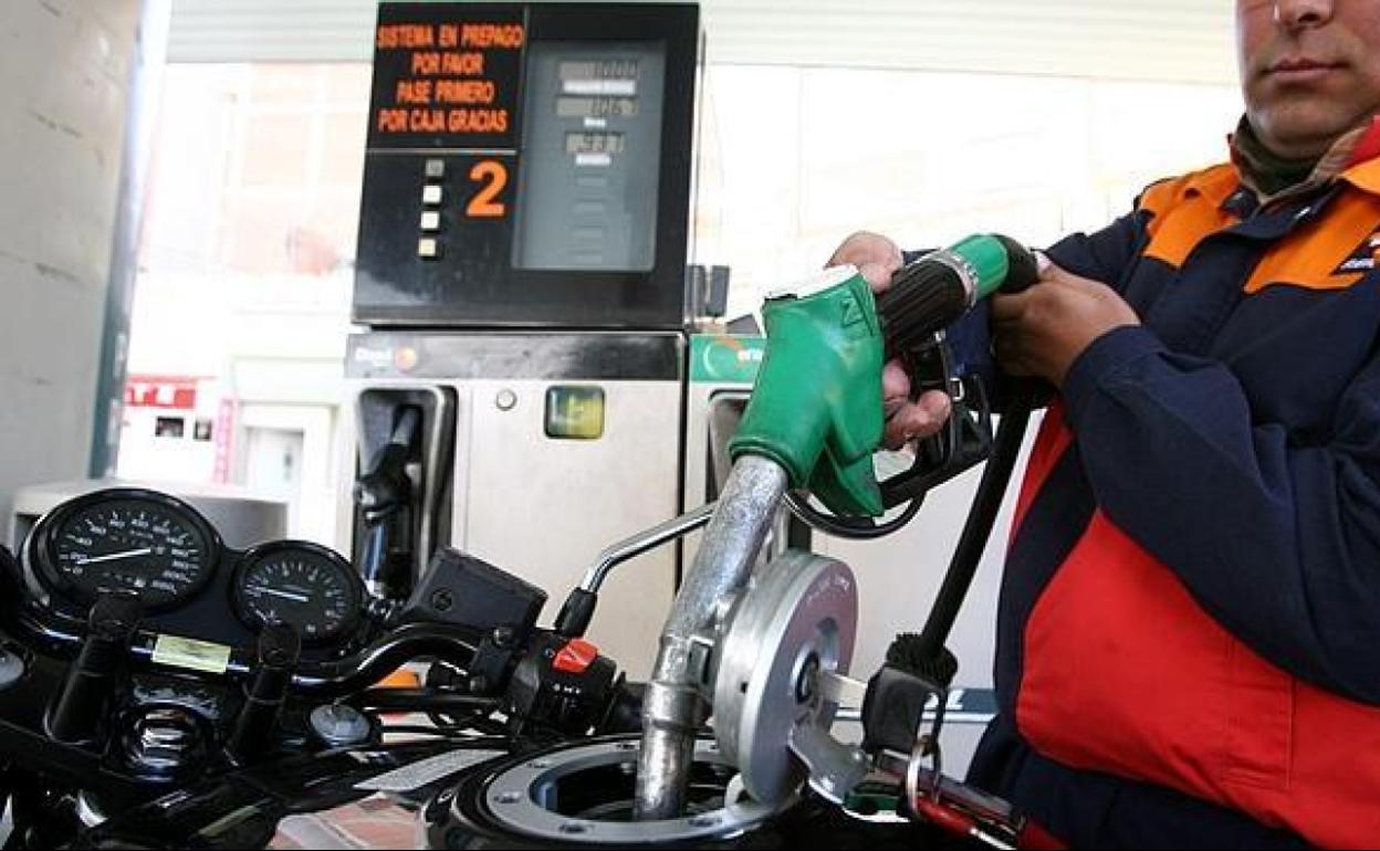 Un empleado de la gasolinera Repsol reposta la motocicleta de un cliente.