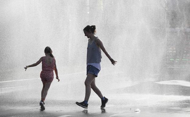 Dos jóvenes se refrescan en una fuente de Vitoria, durante la pasada ola de calor.