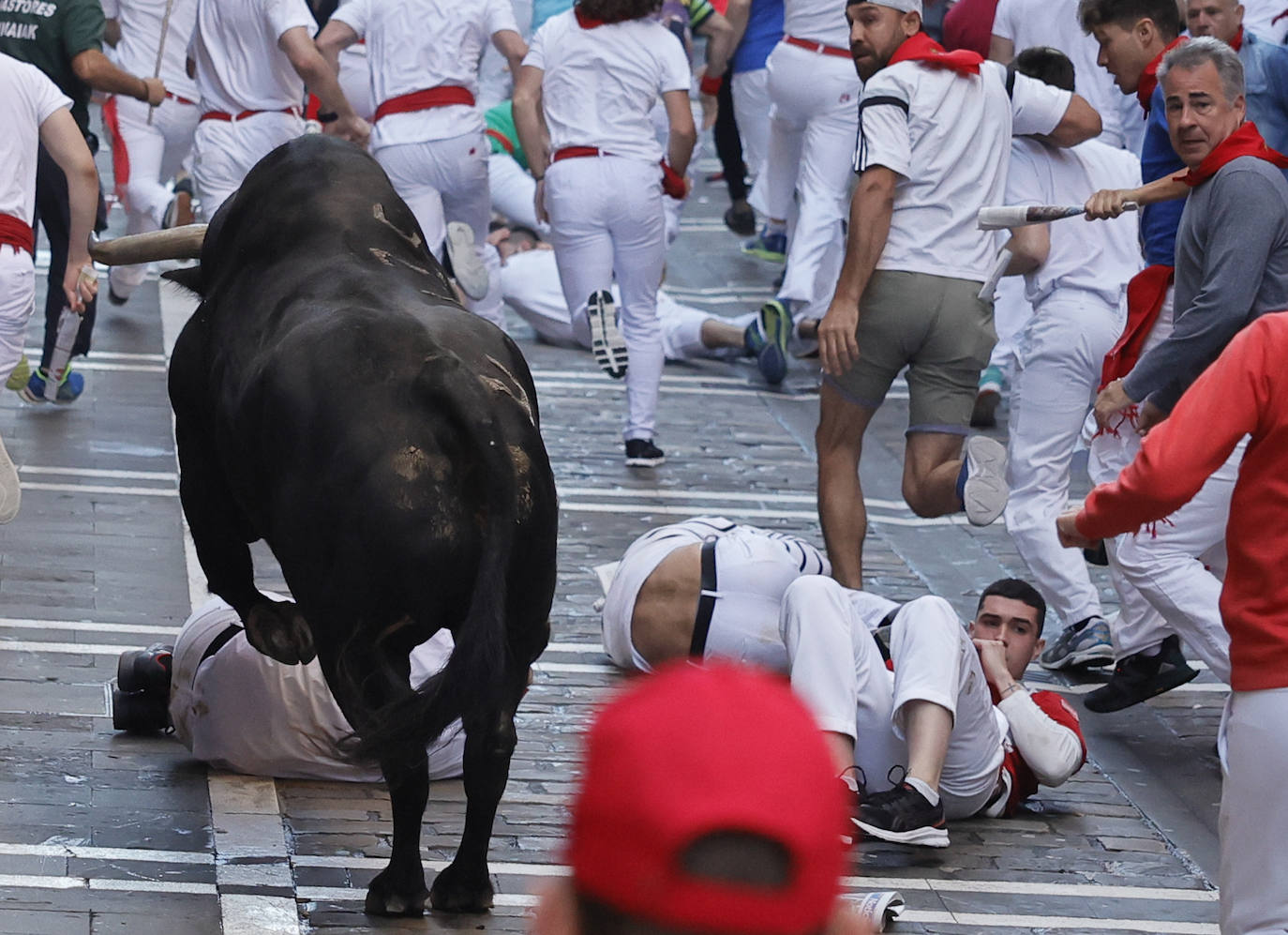 Varios mozos caen ante un toro rezagado en el tramo inicial de la calle de la Estafeta.