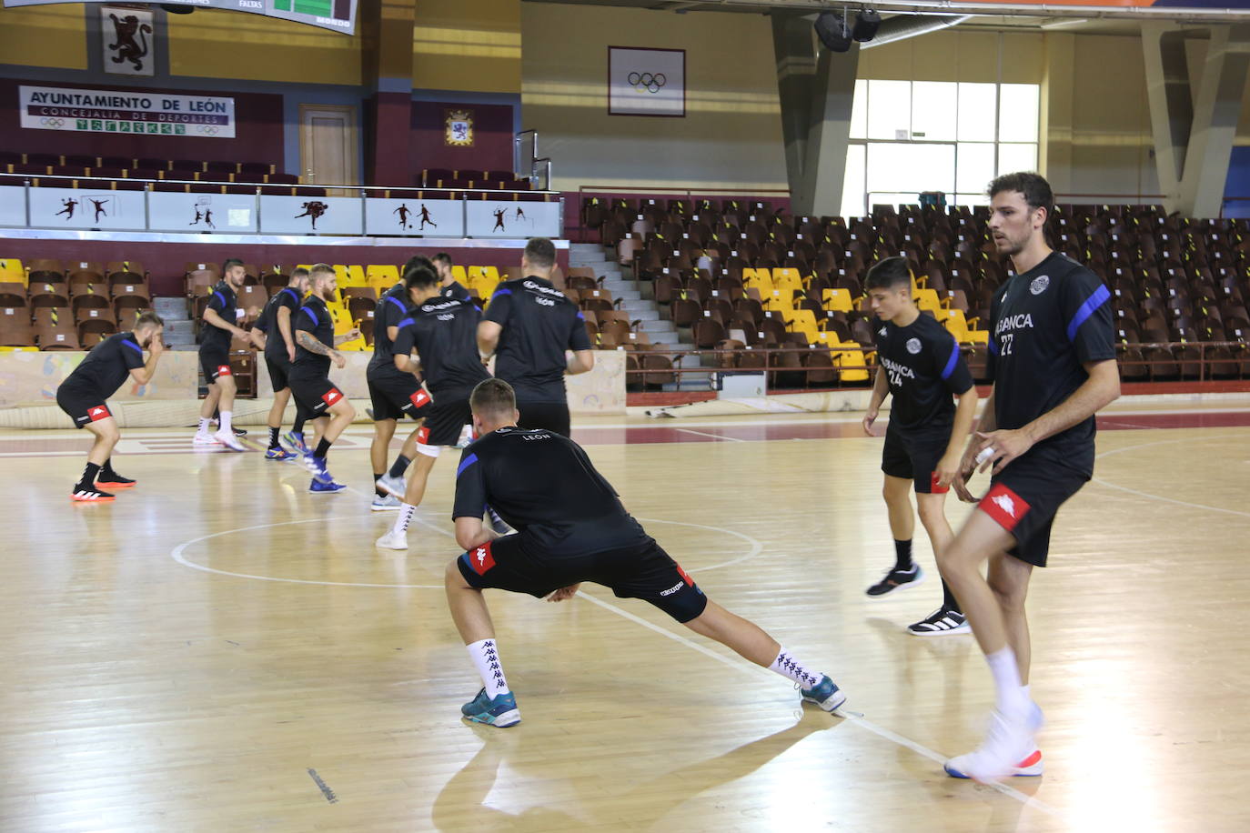 La plantilla del Ademar realiza flexiones en medio de la cancha del Palacio de los Deportes. 