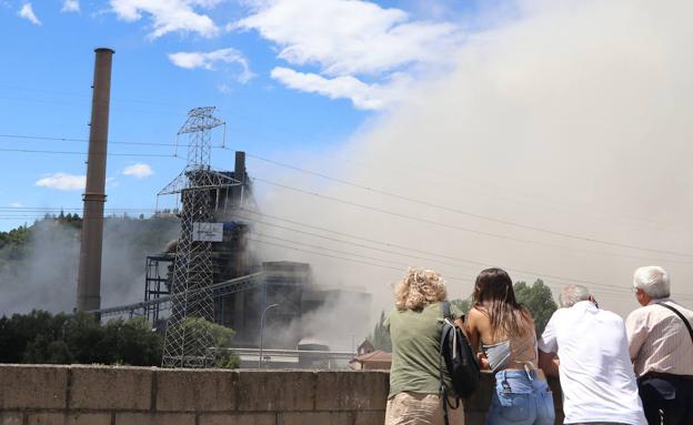 Dos personas se preparan para ver en directo la demolición de la chimenea. 