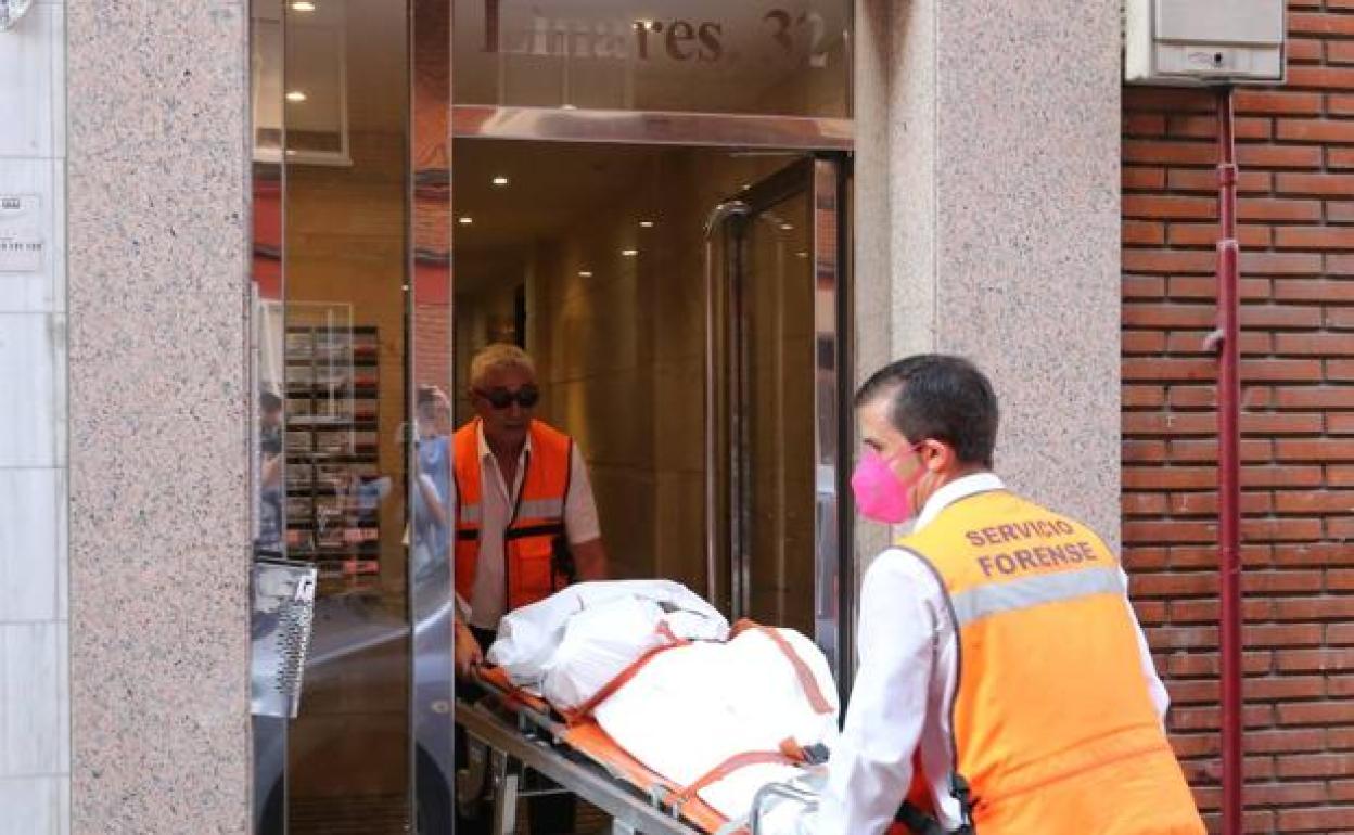 Dos forenses sacan uno de los cuerpos de la calle Linares 32. 