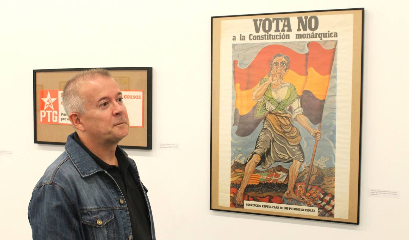 Miguel Gutiérrez psoa con algunos de los carteles que se pueden observar en la exposición.