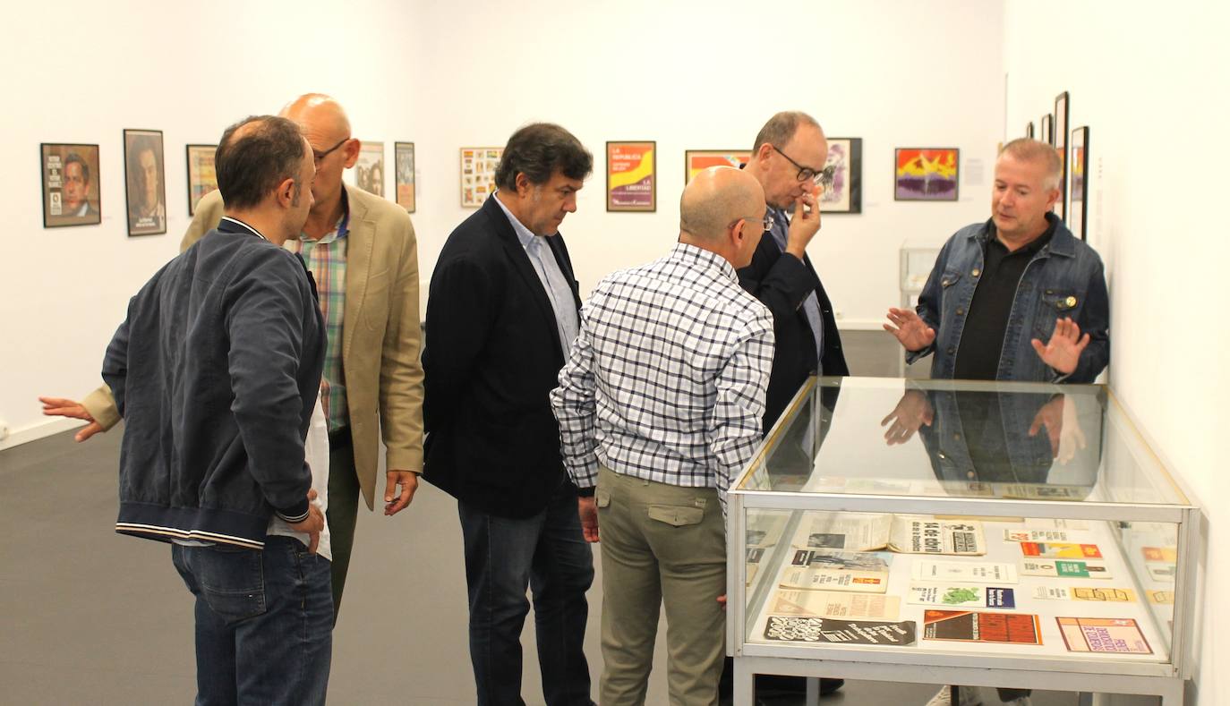 Miguel Gutiérrez psoa con algunos de los carteles que se pueden observar en la exposición.