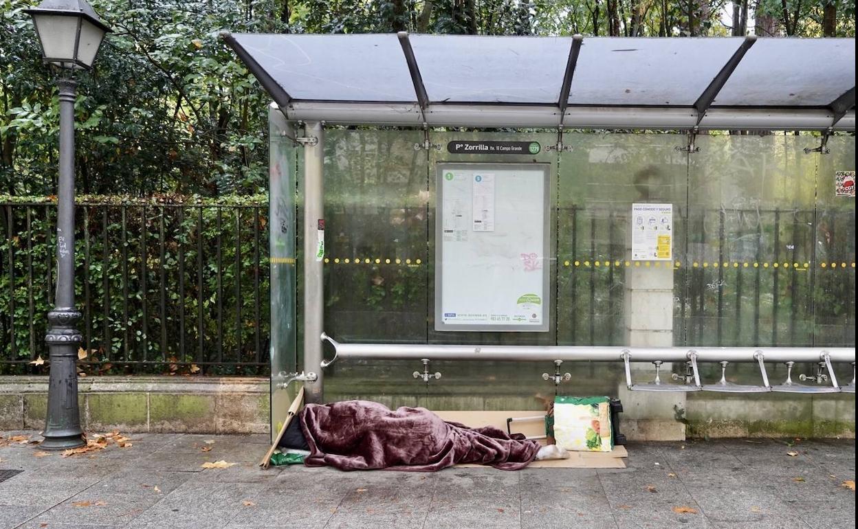 Un sin techo duerme bajo una marquesina en una ciudad de Castilla y León.