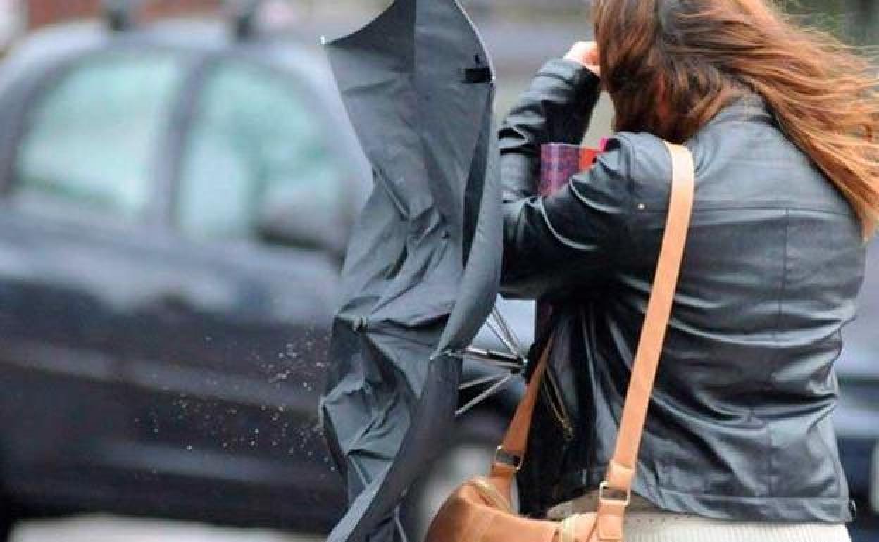 Imagen de una mujer luchando contra el viento un día de tormenta. 