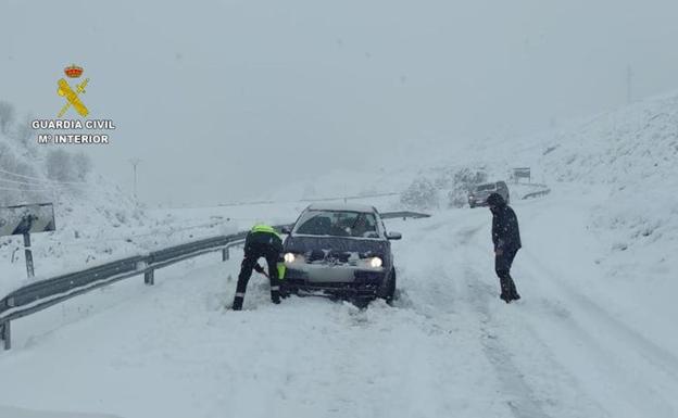 Efectivos de la Guardia Civil, durante el auxilio a uno de los vehículos bloqueados por la nieve. 