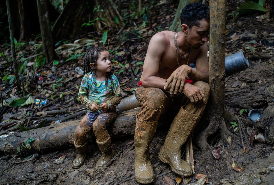 Un hombre y un niño, exhaustos, descansan en el Tapón de Darién. Les queda una semana de caminata aún por delante a través del tramo de terreno selvático de 66 millas entre Colombia y Panamá, el 23 de septiembre. 