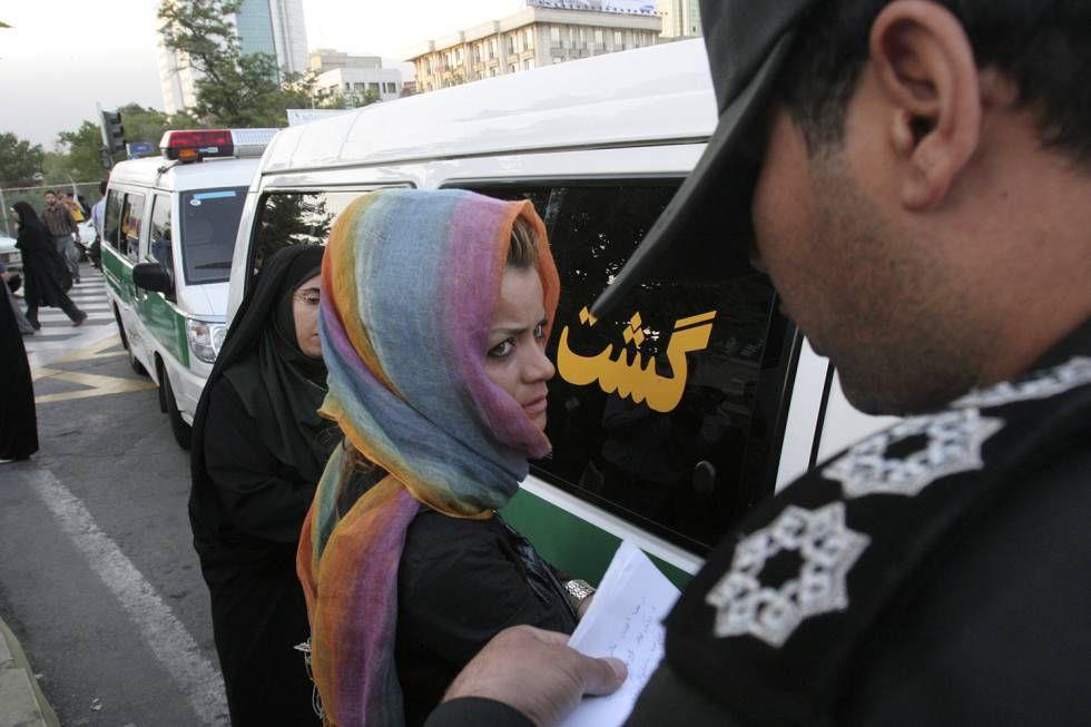 Una pareja perteneciente a la Policía de la moral (ella vestida con el chador oscuro) sanciona a una joven en Teherán por dejar parte de su cabello al descubierto.