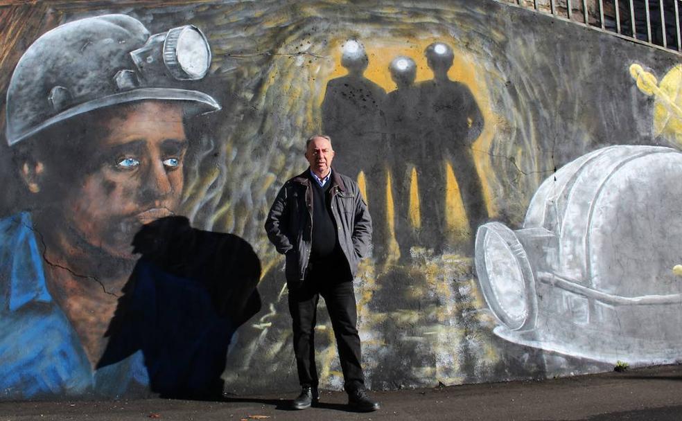 Victorino Lombas, pedáneo de Santa Lucía y exmineros, posa junto a un mural en honor a la minería en la localidad leonesa.