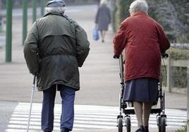 Una pareja de ancianos camina por las calles de León.