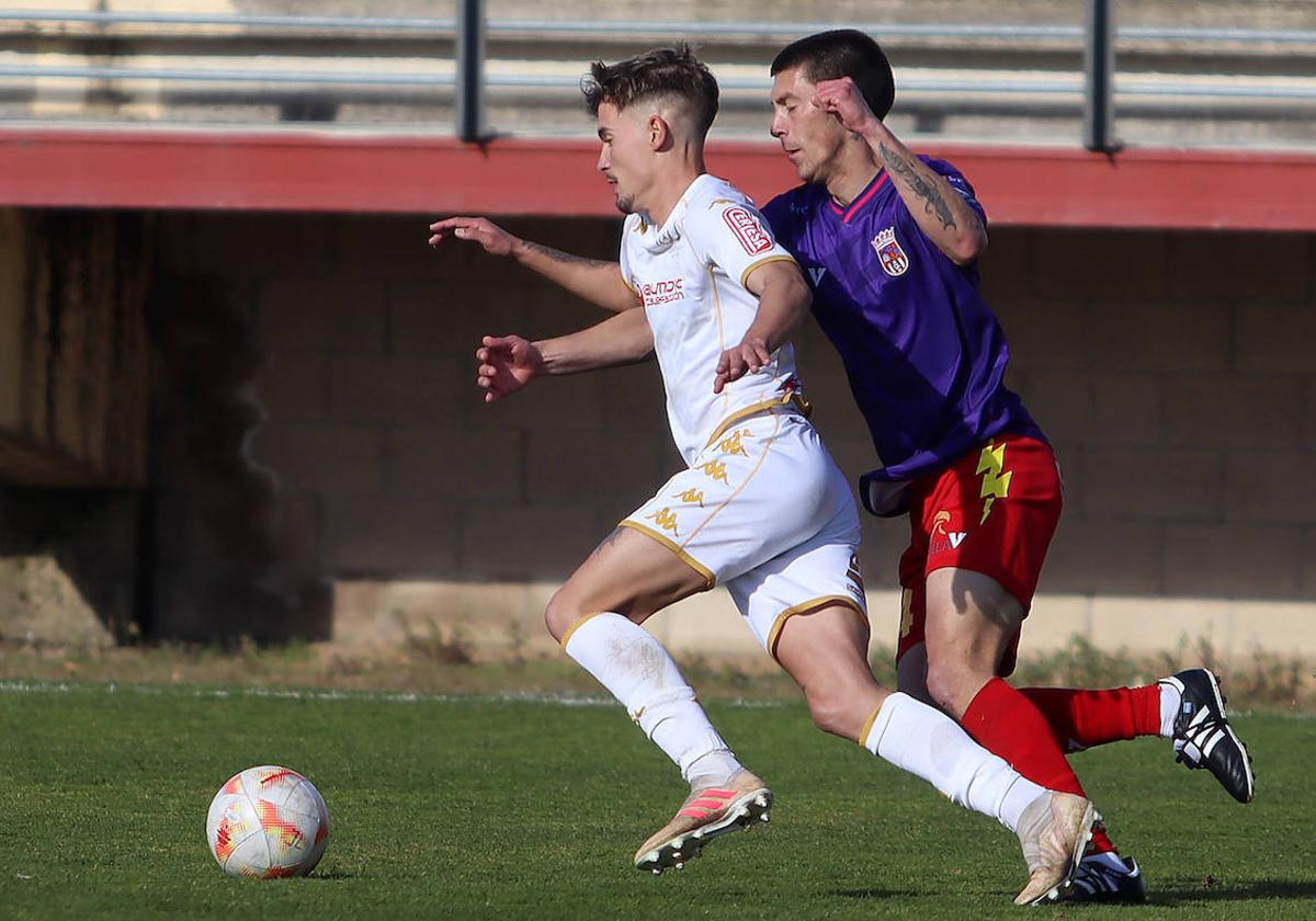 Un jugador del Júpiter Leonés intenta zafarse de la marca del defensa del Palencia CF en una imagen de archivo.