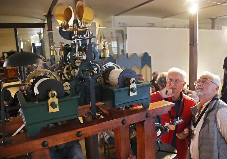 Dos hombres observan el reloj mecánico de Antonio Canseco expuesto en el Museo de Botines.