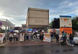 Vecinos del Barrio de Pinilla se manifiestan bajo la lluvia frente al centro de salud.