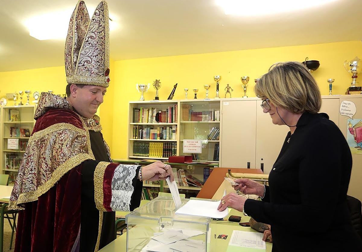 El hostelero Juan López, vota disfrazado de obispo en el Colegio Público La Palomera de León acompañado por el candidato a la reelección, José Antonio Diez.