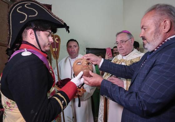 El mayordomo de la cofradía hace entrega de la máscara de San Sebastián a Álvaro Martínez antes del comienzo de la procesión